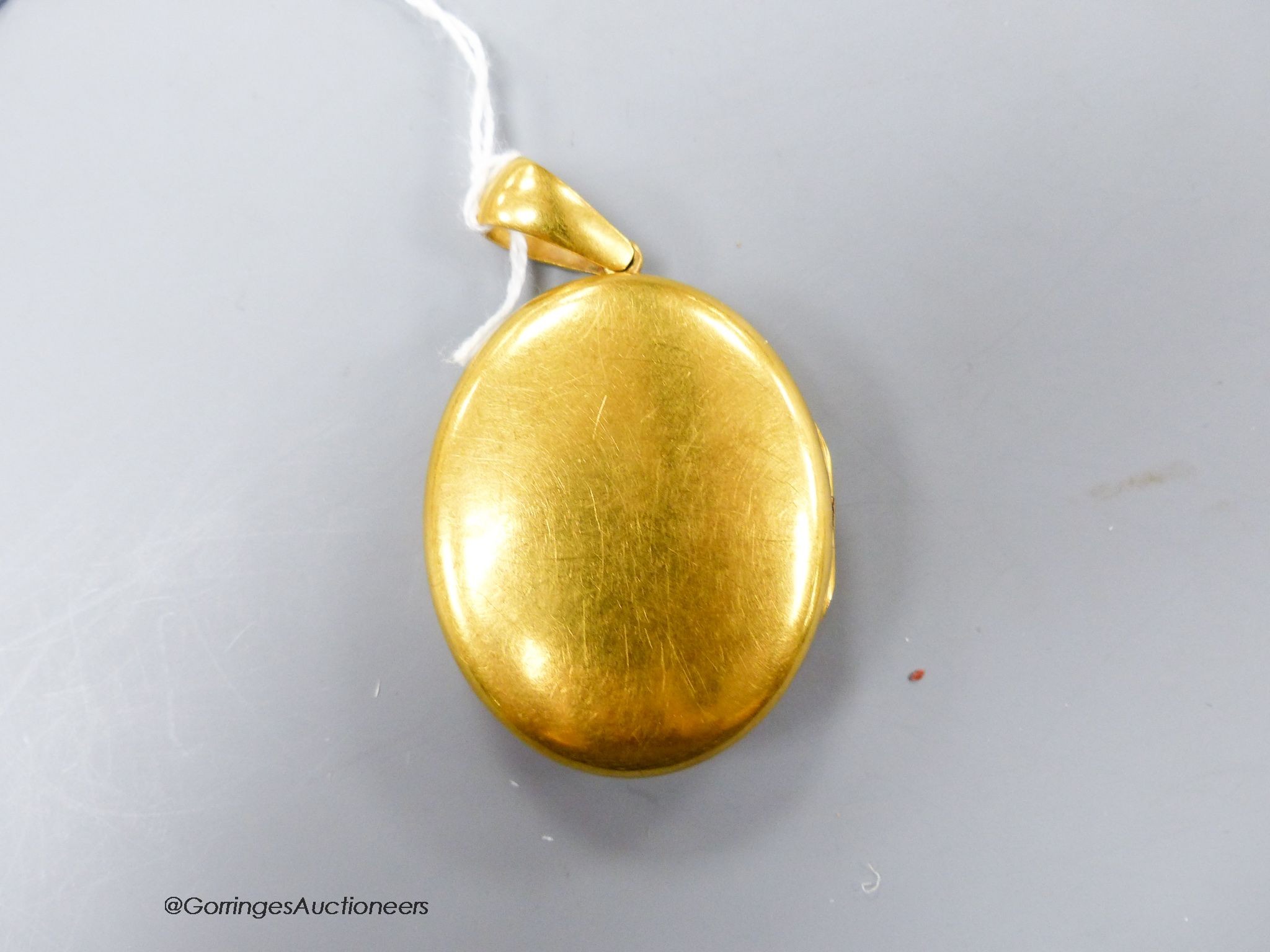 A Victorian yellow metal oval pendant locket with applied monogram, overall 63mm, gross weight 31.9 grams.